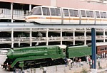 Monorail train passing above steam locomotive 3801 stopped with passenger train thumbnail